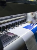 Large format inkjet printer machine working on vinyl paper in workplace