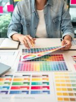 Young creative graphic designer working on color selection and drawing on graphics tablet at workplace, Color swatch samples chart for selection coloring in inspiration to create new collection.